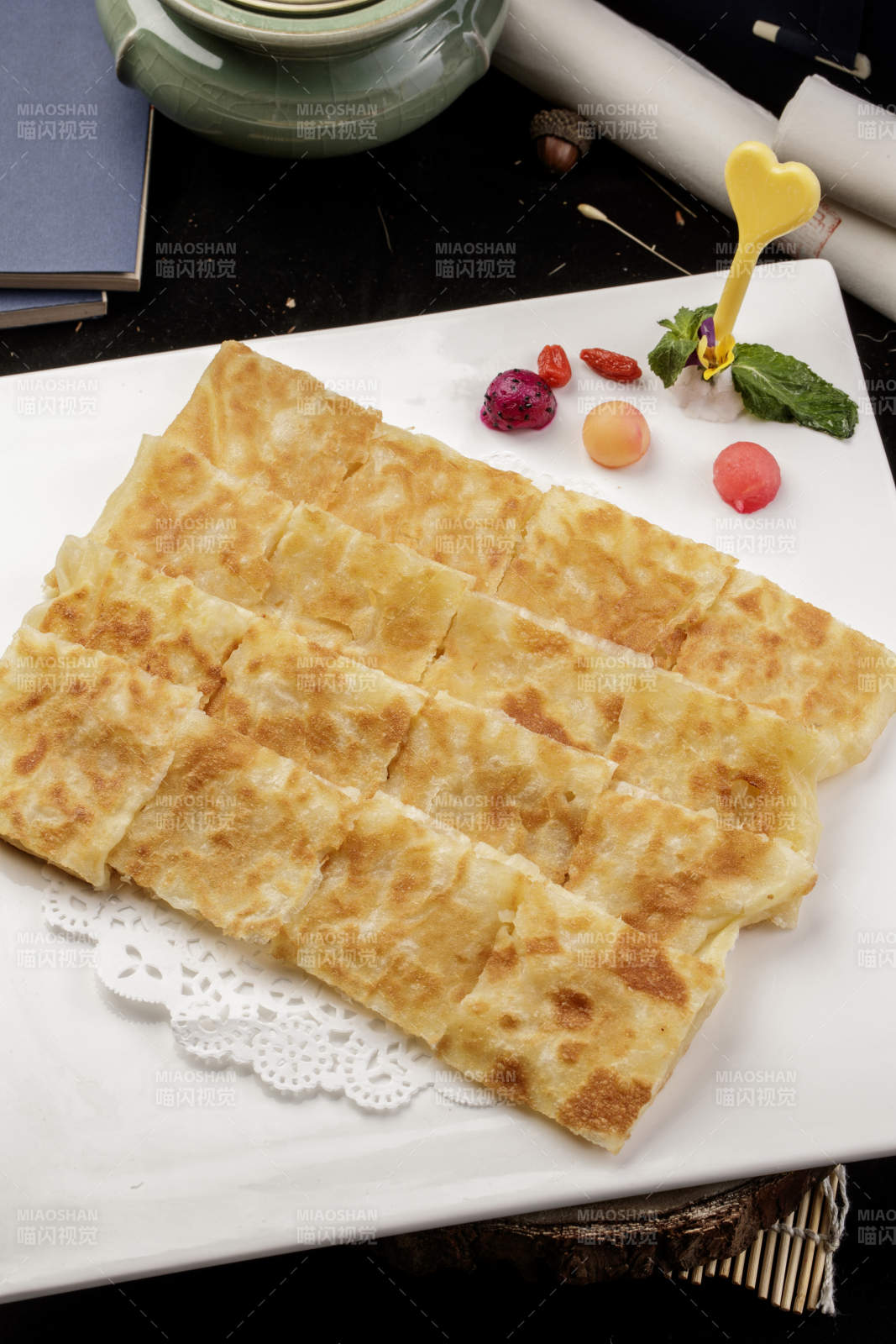 方形瓷盘装的印度飞饼摆放在樟木砧板上图片