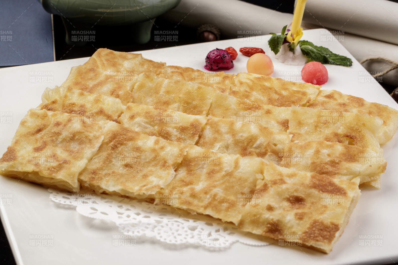 方形瓷盘装的印度飞饼摆放在樟木砧板上图片