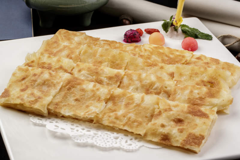 方形瓷盘装的印度飞饼摆放在樟木砧板上图片