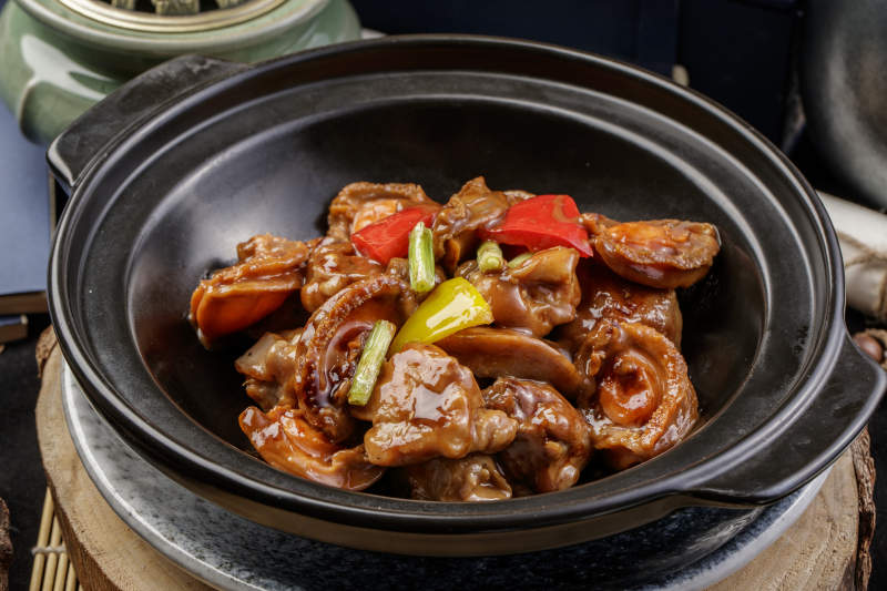 黑色砂锅装的砂锅鲍鱼鸡块摆放在樟木砧板上图片