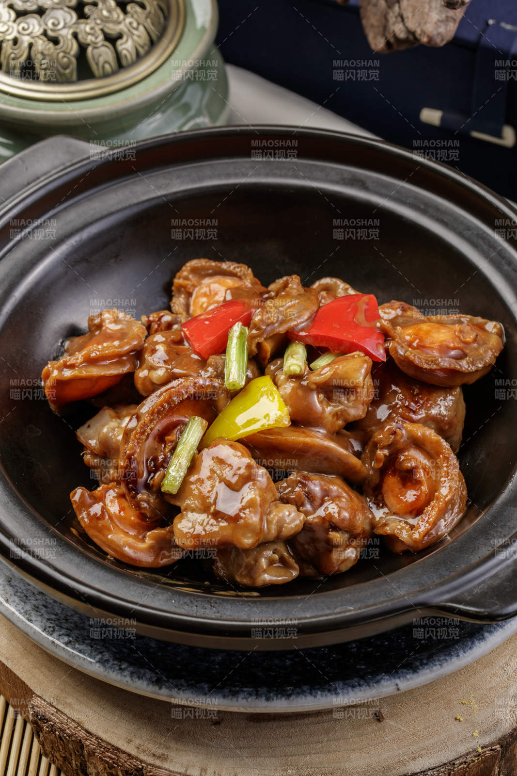 黑色砂锅装的砂锅鲍鱼鸡块摆放在樟木砧板上图片