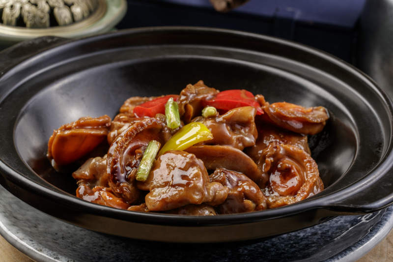 黑色砂锅装的砂锅鲍鱼鸡块摆放在樟木砧板上图片