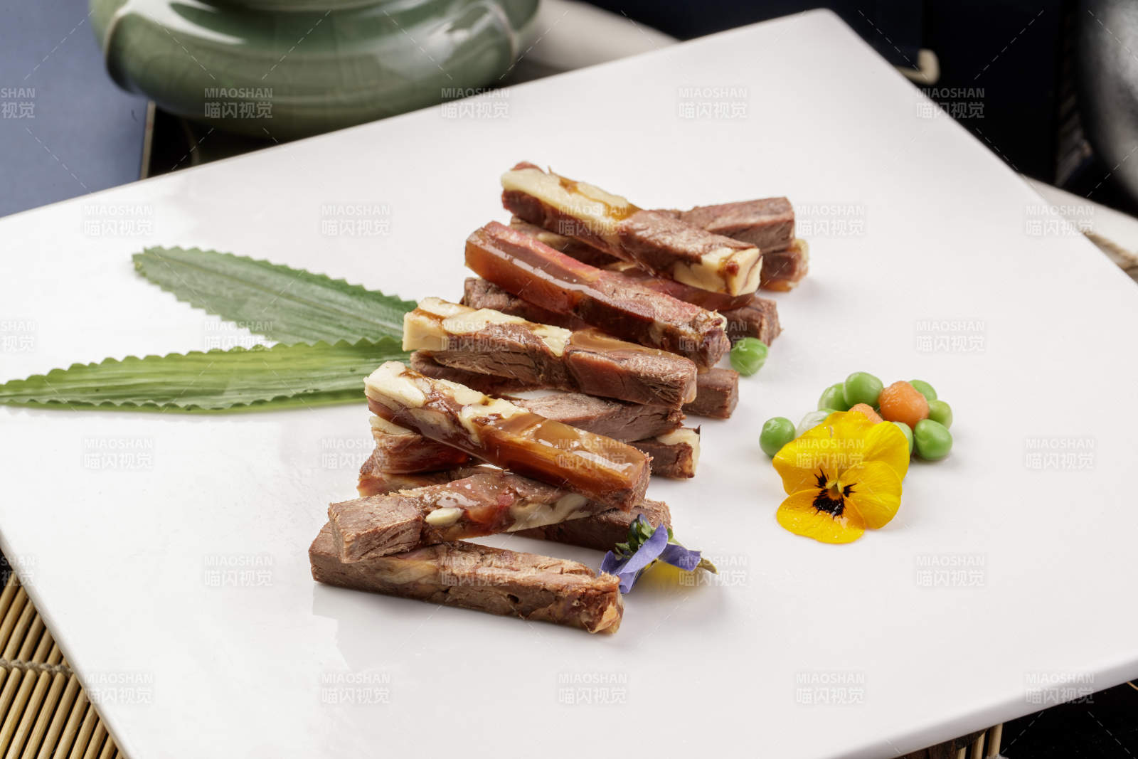 方形瓷盘装的桃仁水晶驴肉摆放在寿司帘上图片