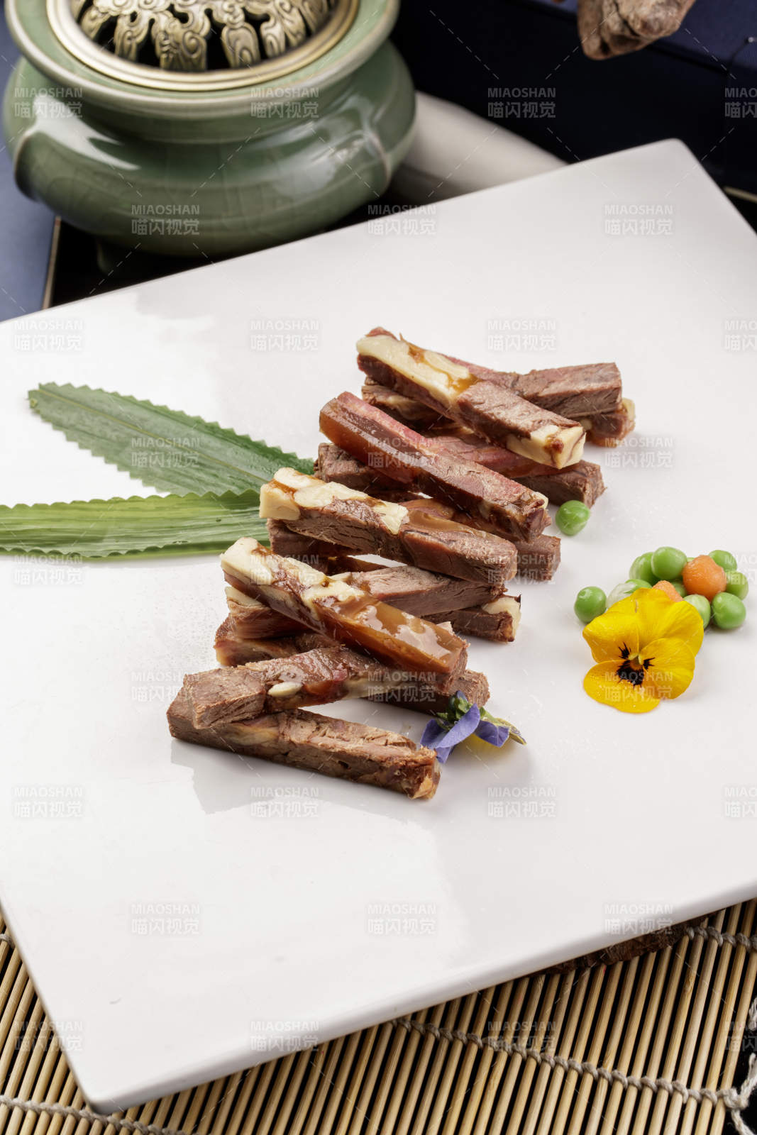 方形瓷盘装的桃仁水晶驴肉摆放在寿司帘上图片