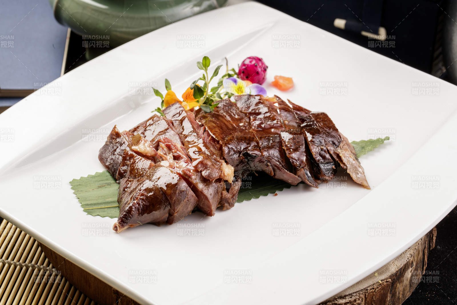 白瓷盘装的苏州酱鸭摆放在寿司帘上图片