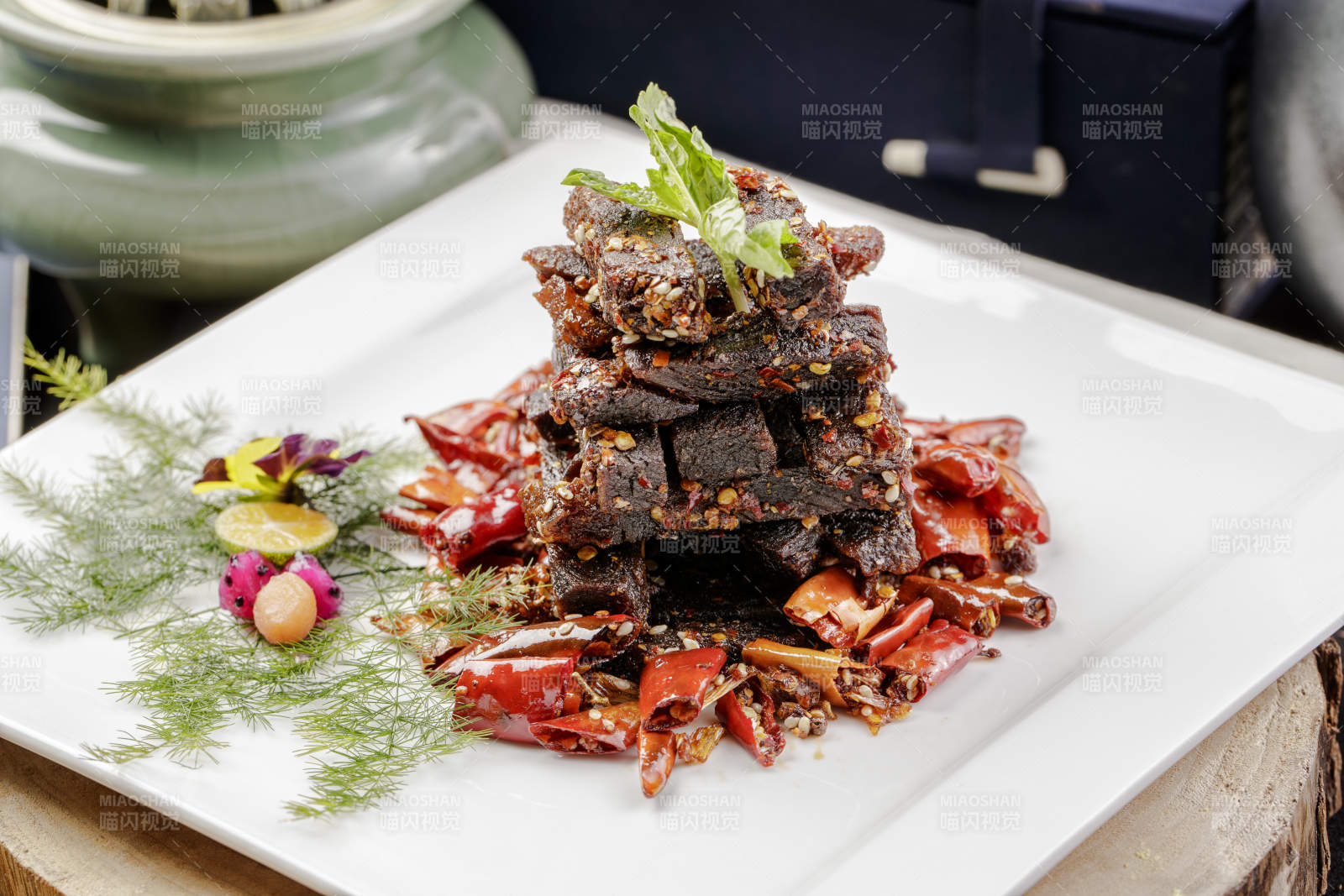 方形瓷盘装的麻辣牛肉摆放在樟木砧板上图片