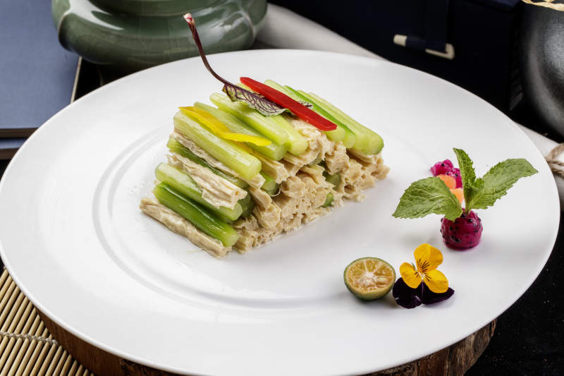 圆形白色瓷盘装的乳瓜腐竹摆放在樟木砧板上图片