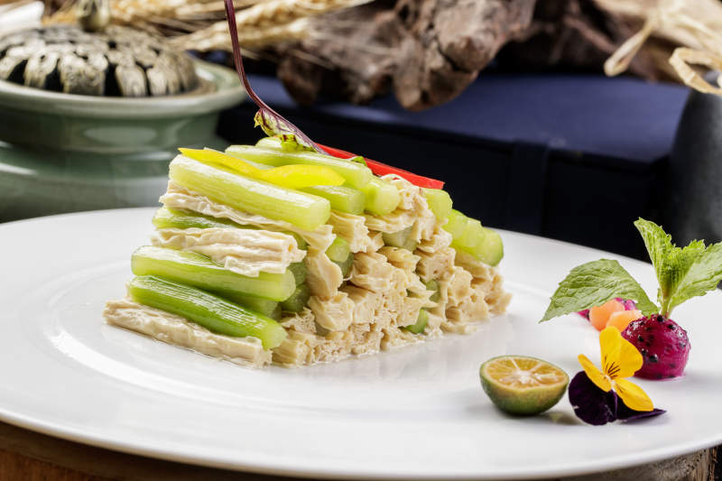 圆形白色瓷盘装的乳瓜腐竹摆放在樟木砧板上图片