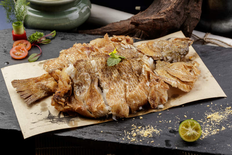 香酥炸高背鲫鱼摆放在黑色背景上图片