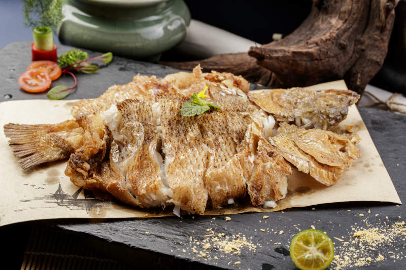 香酥炸高背鲫鱼摆放在黑色背景上图片