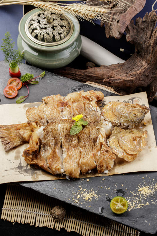 香酥炸高背鲫鱼摆放在黑色背景上图片