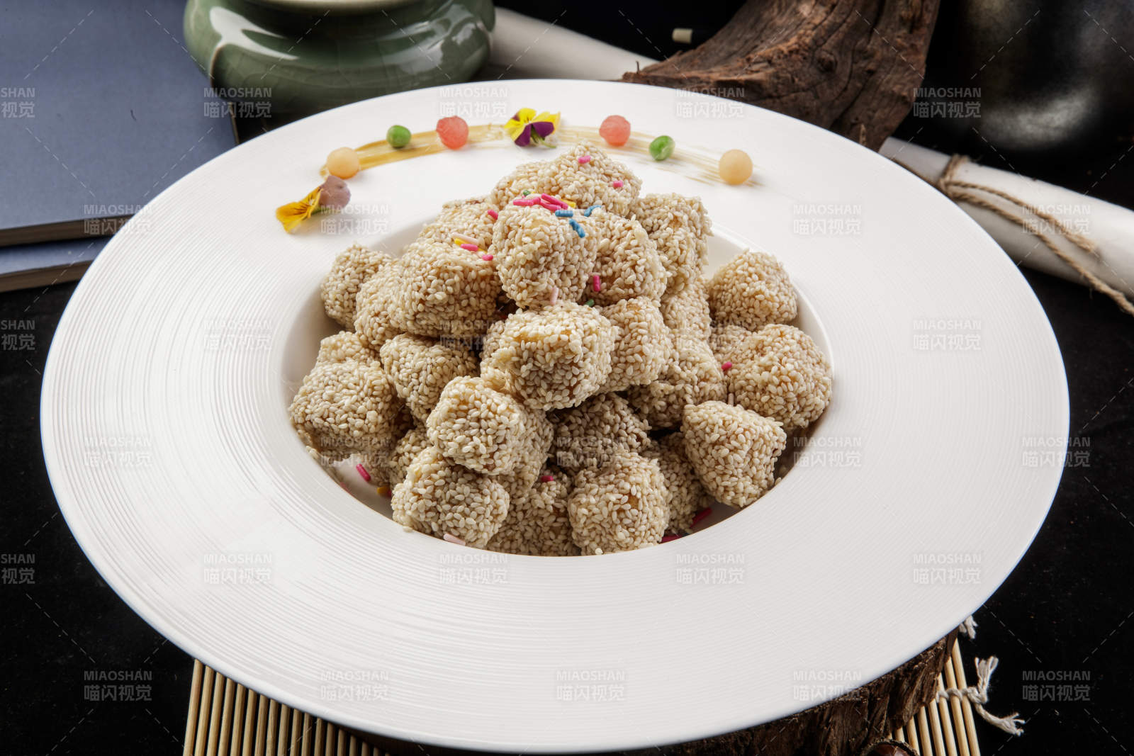 圆形瓷盘装的麻仁红薯摆放在寿司帘上图片