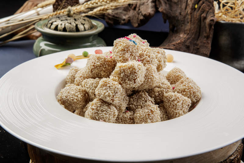 圆形瓷盘装的麻仁红薯摆放在寿司帘上图片