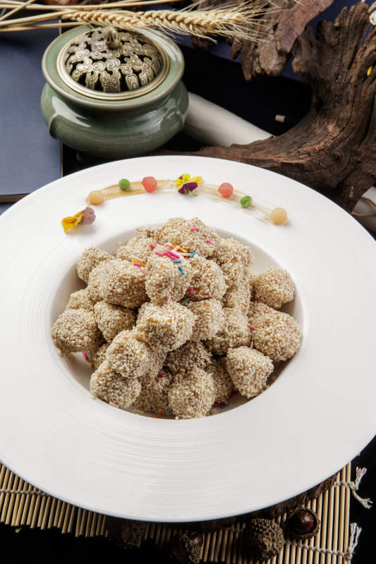 圆形瓷盘装的麻仁红薯摆放在寿司帘上图片