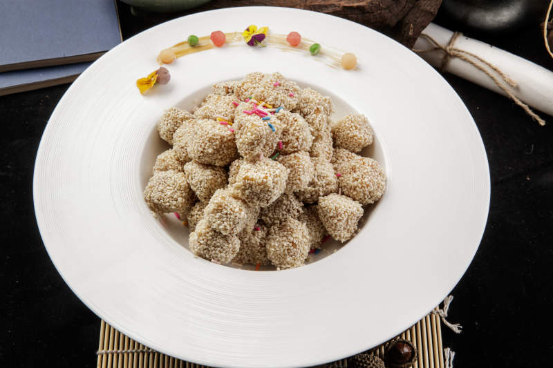 圆形瓷盘装的麻仁红薯摆放在寿司帘上图片