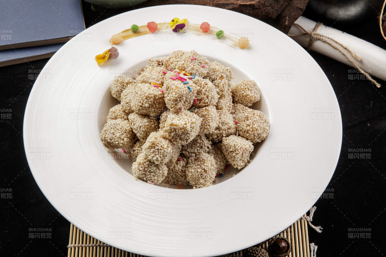 圆形瓷盘装的麻仁红薯摆放在寿司帘上图片