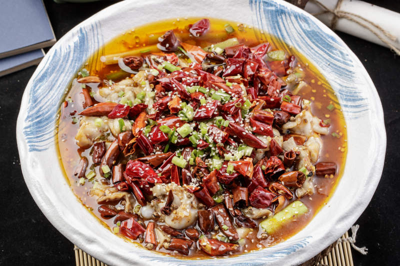 白色花纹盘装的香辣馋嘴蛙摆放在寿司帘上图片