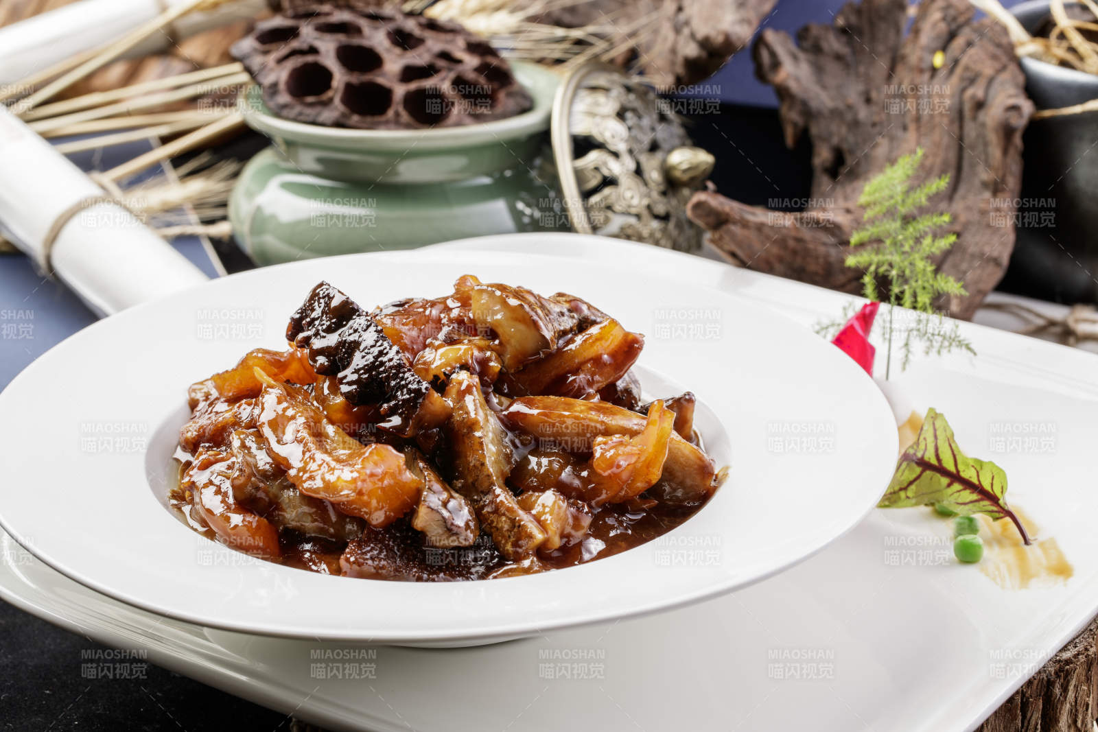 圆形白瓷盘装的葱烧梅花参摆放在黑色背景上图片