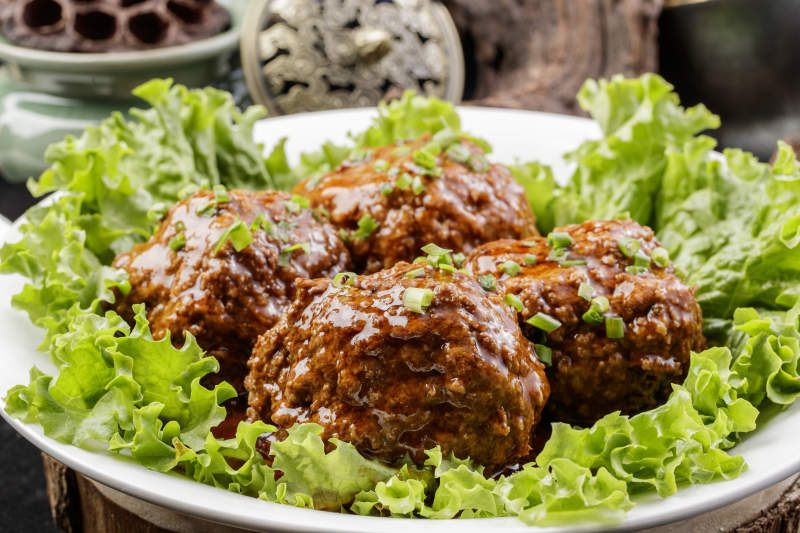 红烧四喜丸子铁狮子头摆放在樟木砧板上图片