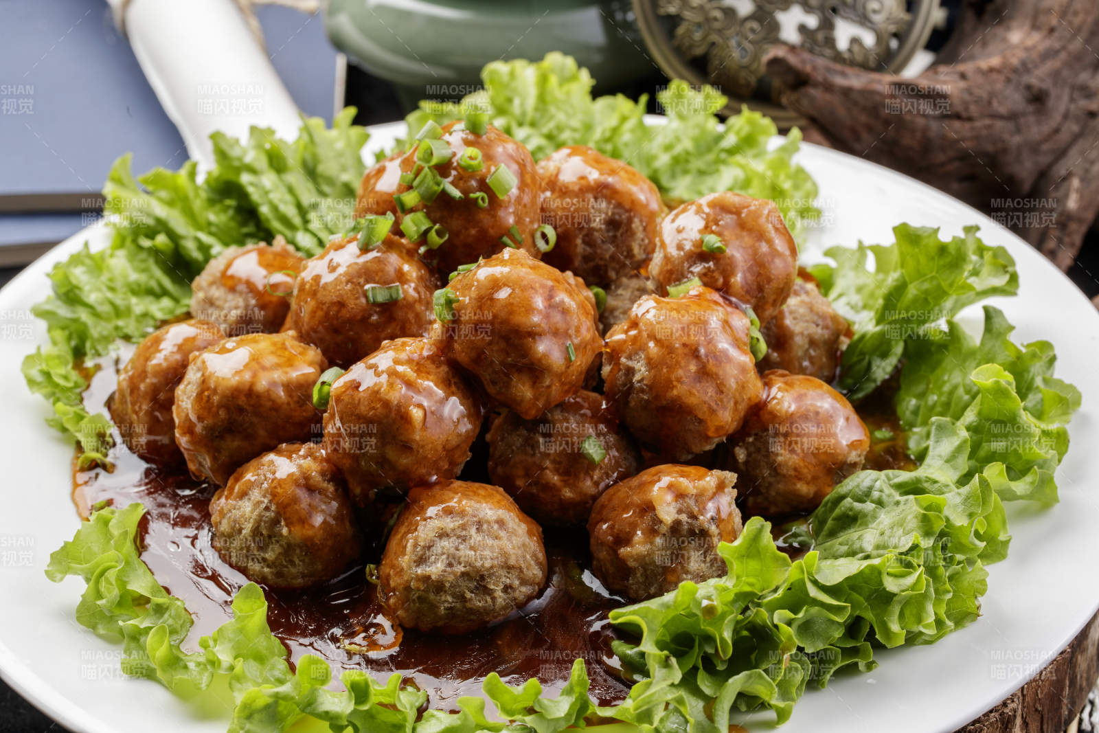 白色圆瓷盘装的红烧丸子摆放在樟木砧板上图片