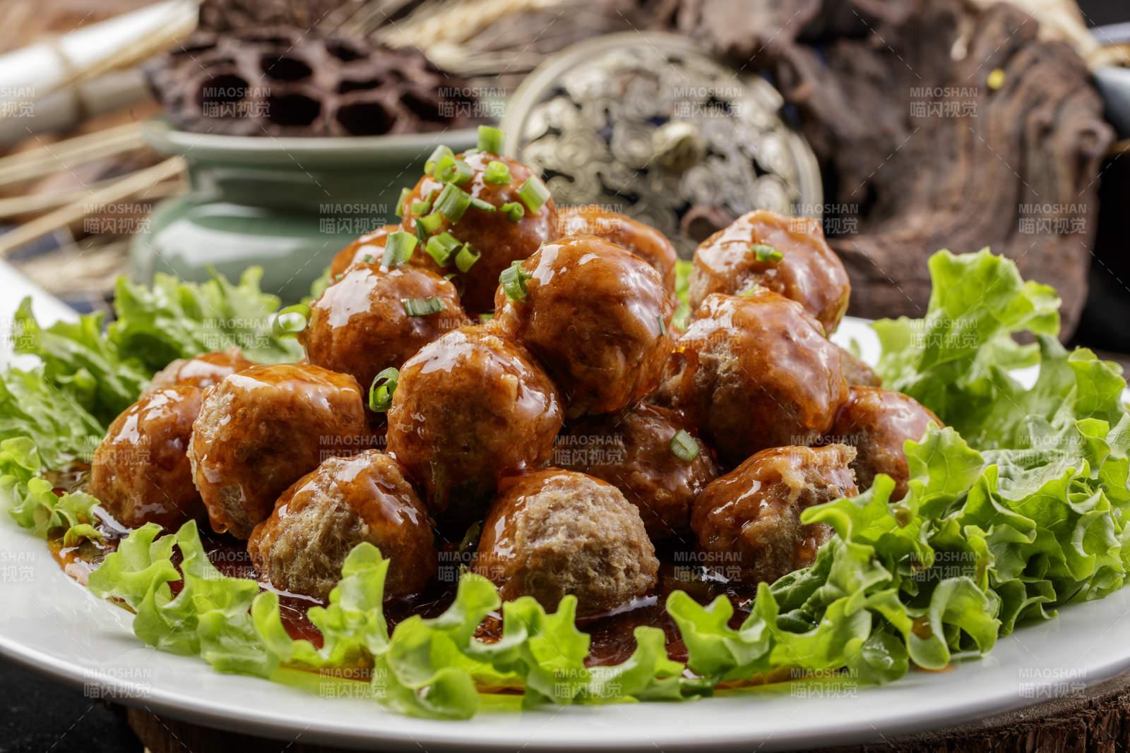 白色圆瓷盘装的红烧丸子摆放在樟木砧板上图片