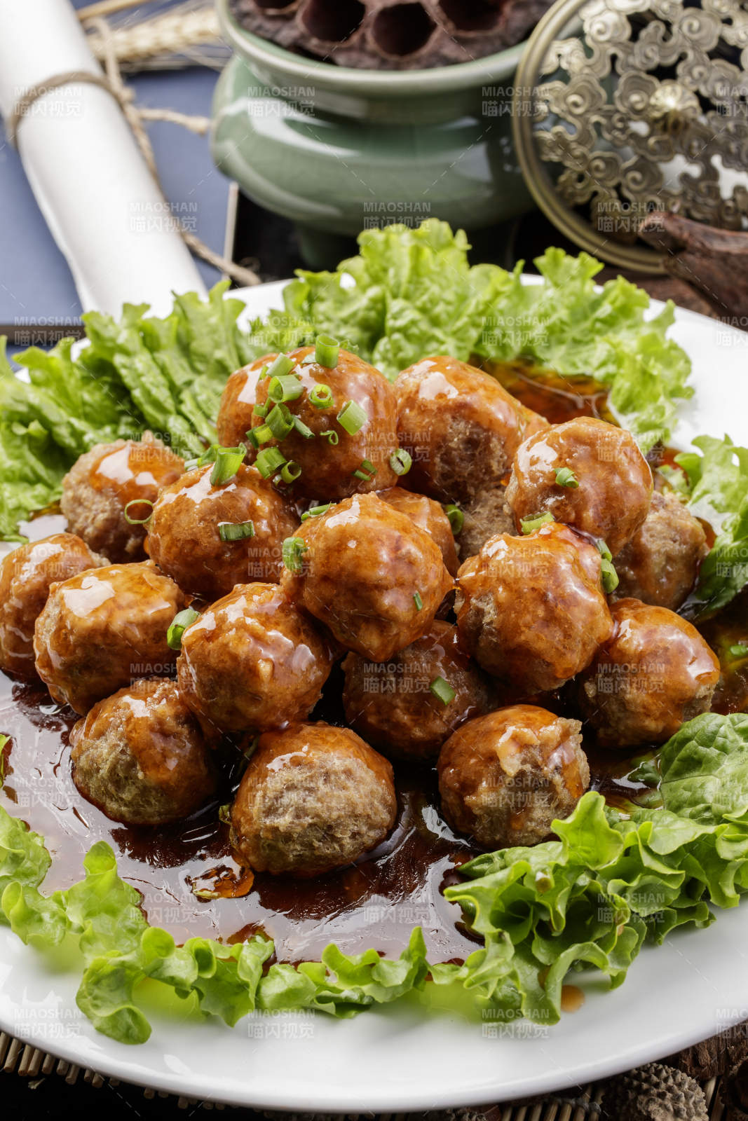 白色圆瓷盘装的红烧丸子摆放在樟木砧板上图片