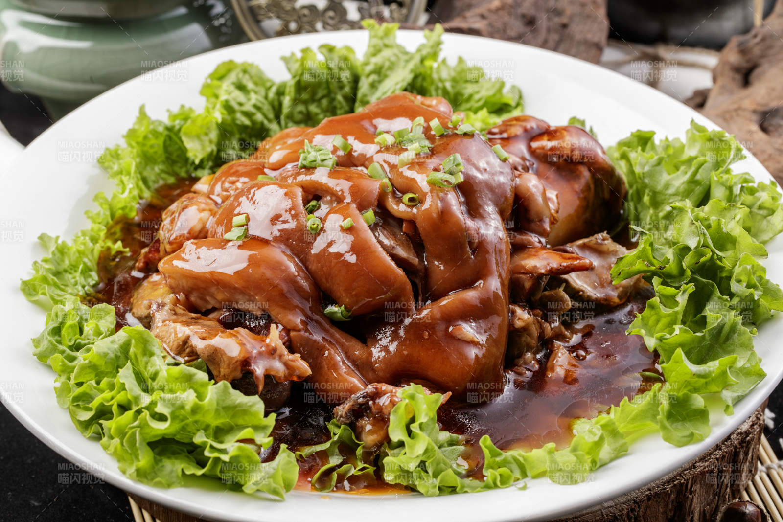 圆形瓷盘装的红扒大肘子摆放在樟木砧板上图片