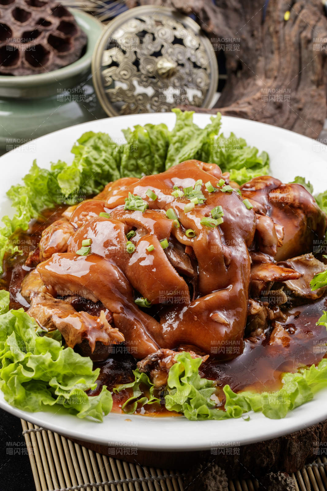 圆形瓷盘装的红扒大肘子摆放在樟木砧板上图片