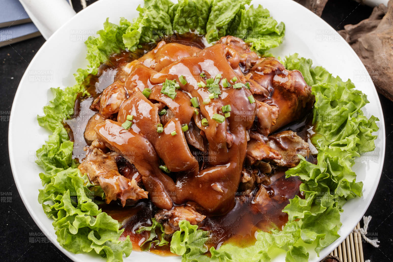 圆形瓷盘装的红扒大肘子摆放在樟木砧板上图片