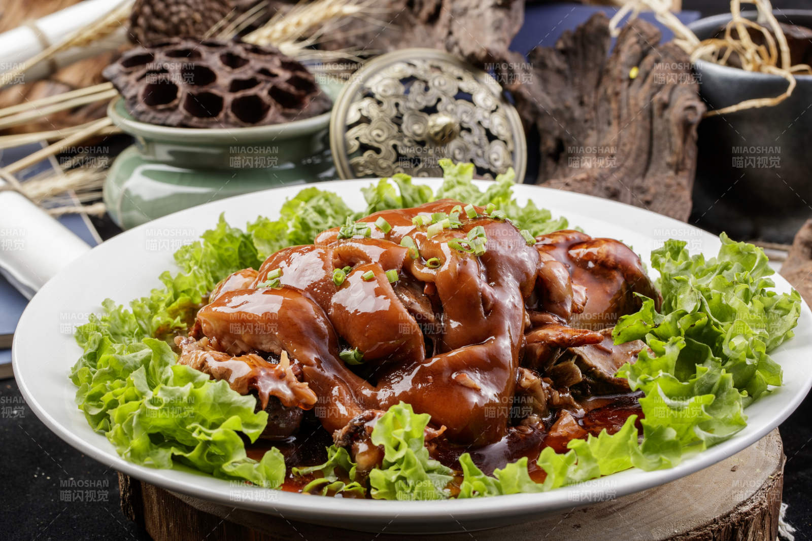 圆形瓷盘装的红扒大肘子摆放在樟木砧板上图片