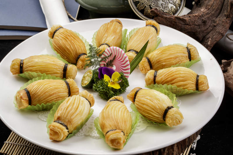 制作精美的泰国榴莲酥摆放在米黄色磁盘上图片