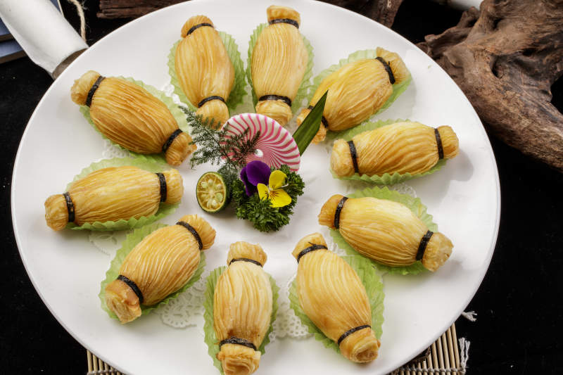 制作精美的泰国榴莲酥摆放在米黄色磁盘上图片