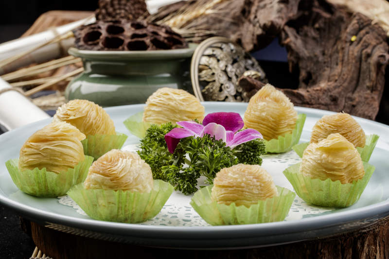 青瓷盘装的木瓜酥摆放在寿司帘上图片