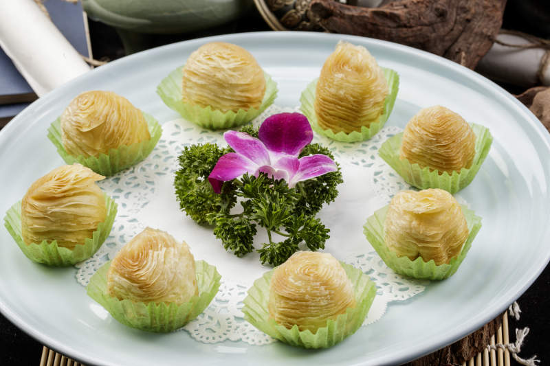 青瓷盘装的木瓜酥摆放在寿司帘上图片