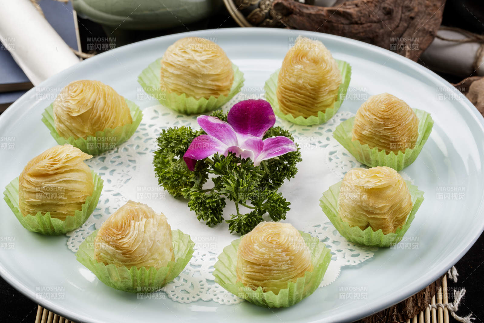 青瓷盘装的木瓜酥摆放在寿司帘上图片