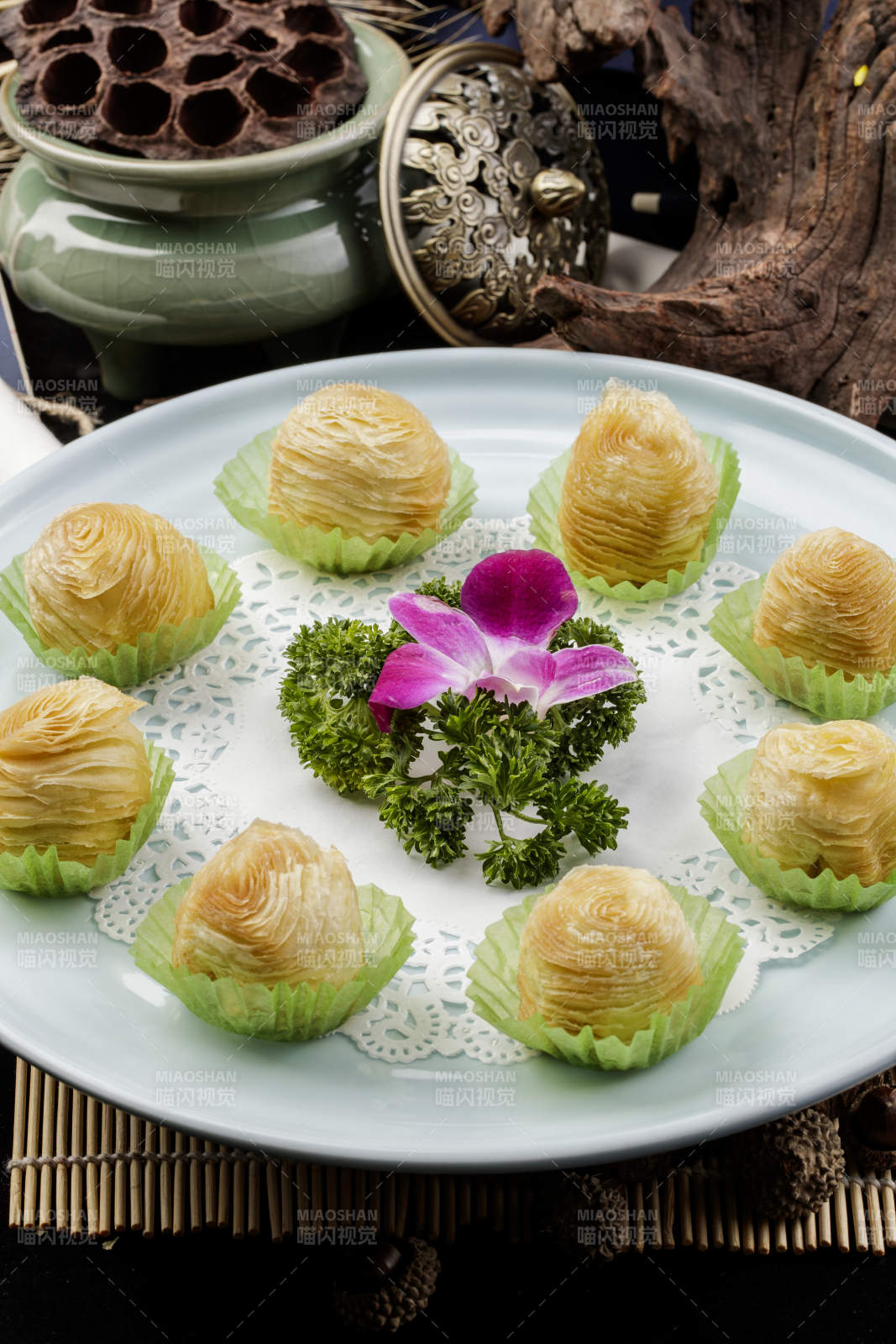 青瓷盘装的木瓜酥摆放在寿司帘上图片