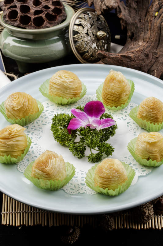 青瓷盘装的木瓜酥摆放在寿司帘上图片