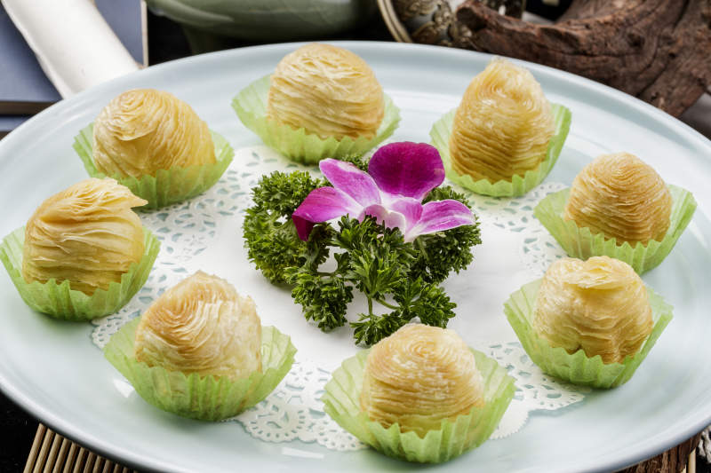 青瓷盘装的木瓜酥摆放在寿司帘上图片