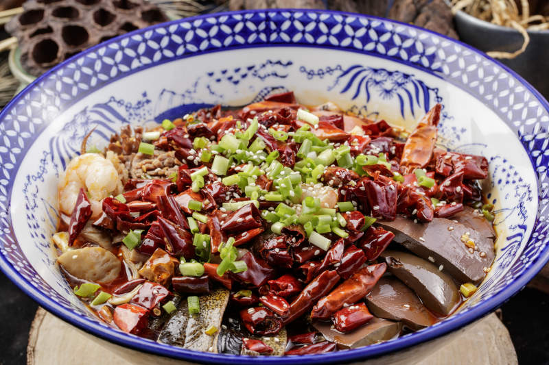 青花瓷盆装的海鲜毛血旺摆放在樟木砧板上图片