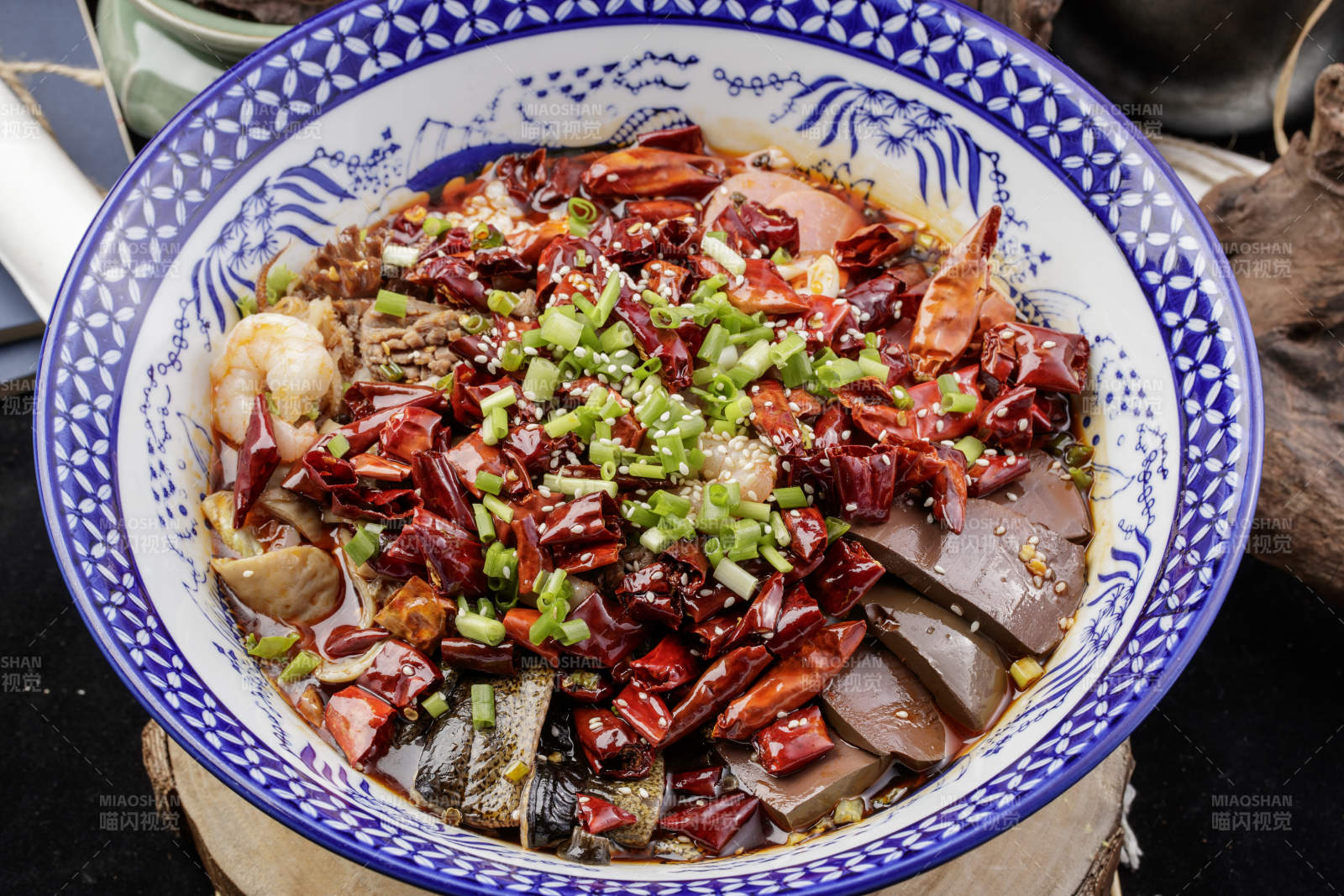青花瓷盆装的海鲜毛血旺摆放在樟木砧板上图片