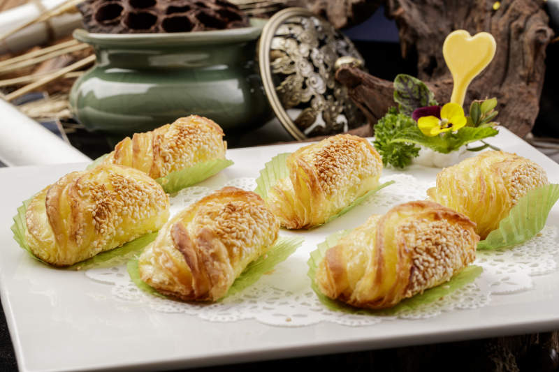 方形瓷盘装的半打榴莲酥摆放在黑色背景上图片