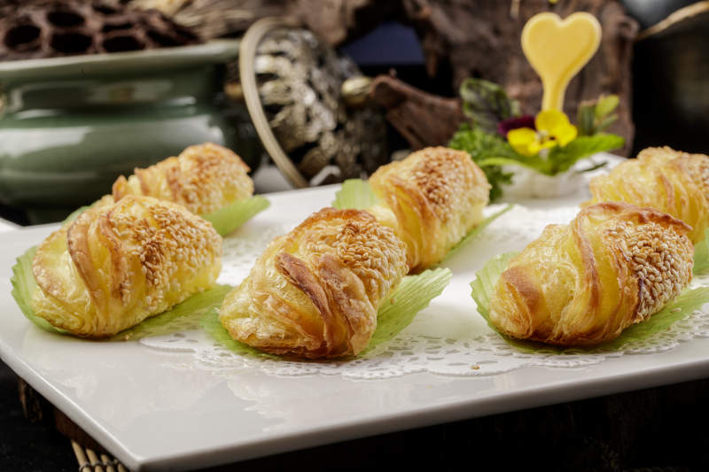 方形瓷盘装的半打榴莲酥摆放在黑色背景上图片