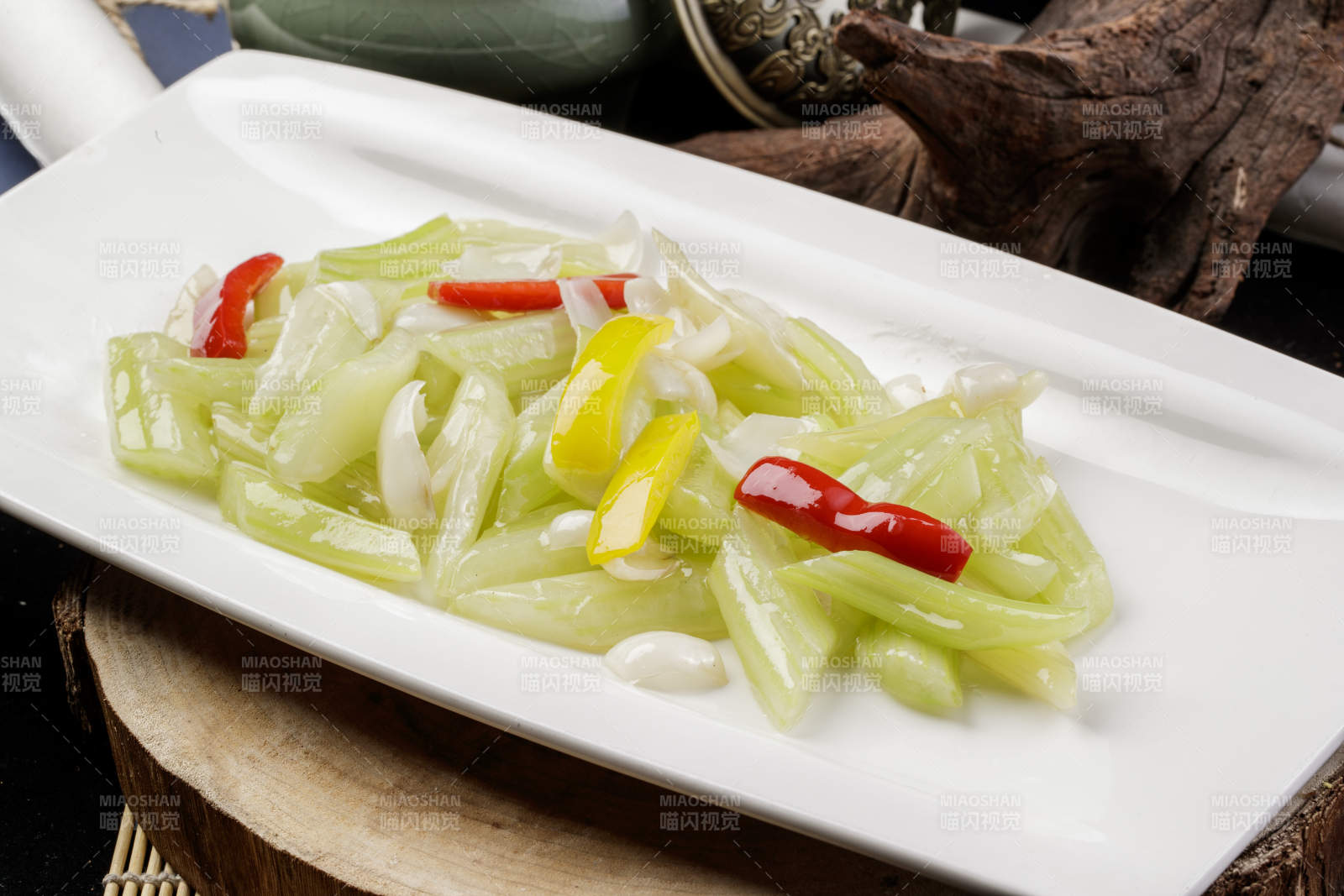 长方形瓷盘装的西芹炒百合摆放在樟木砧板上图片