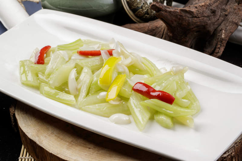 长方形瓷盘装的西芹炒百合摆放在樟木砧板上图片