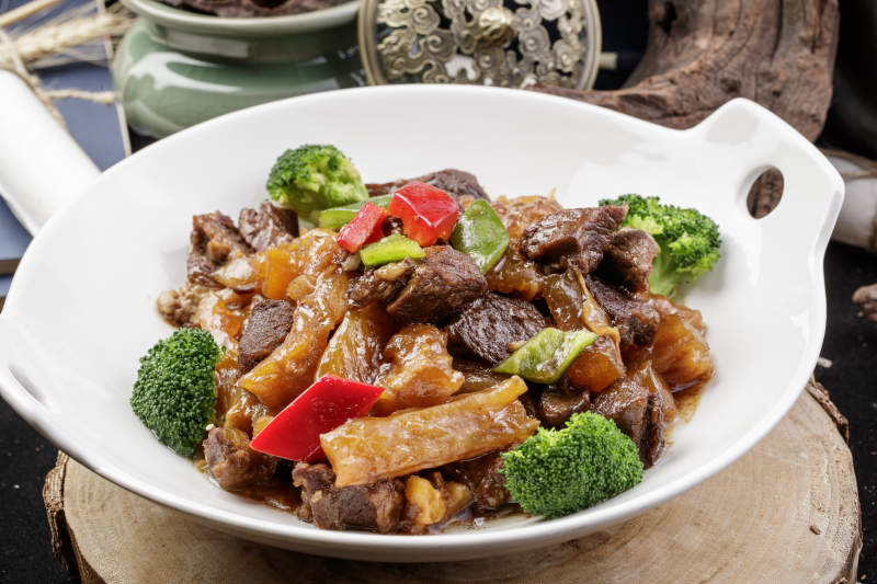 白色耳盘装的牛五花烧蹄筋摆放在樟木砧板上图片