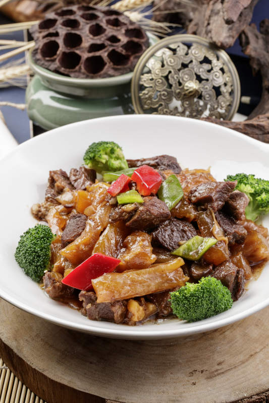 白色耳盘装的牛五花烧蹄筋摆放在樟木砧板上图片