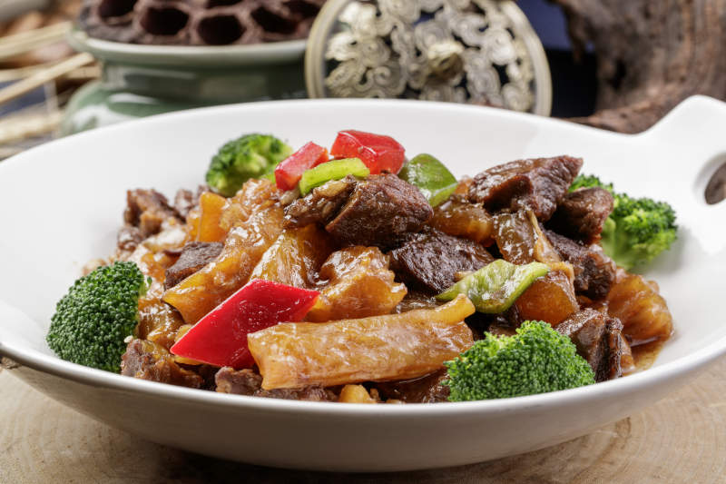 白色耳盘装的牛五花烧蹄筋摆放在樟木砧板上图片