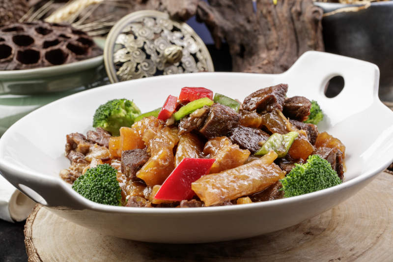 白色耳盘装的牛五花烧蹄筋摆放在樟木砧板上图片