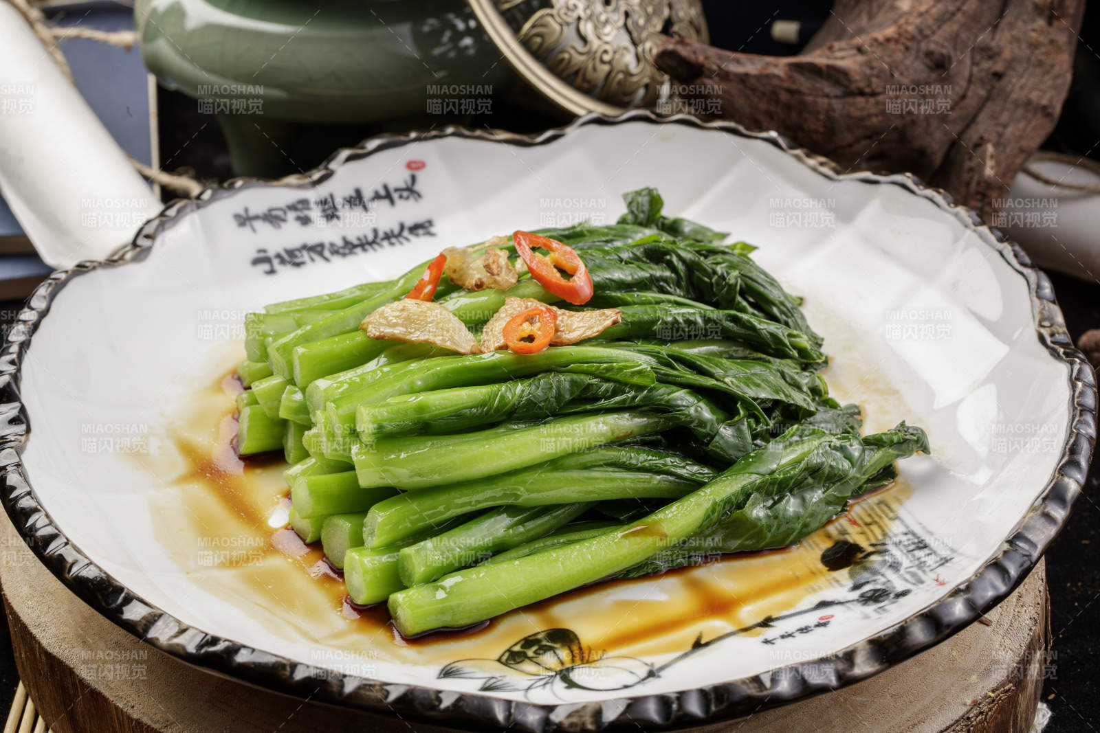 白色瓷盘装的炝炒芥蓝摆放在樟木砧板上图片