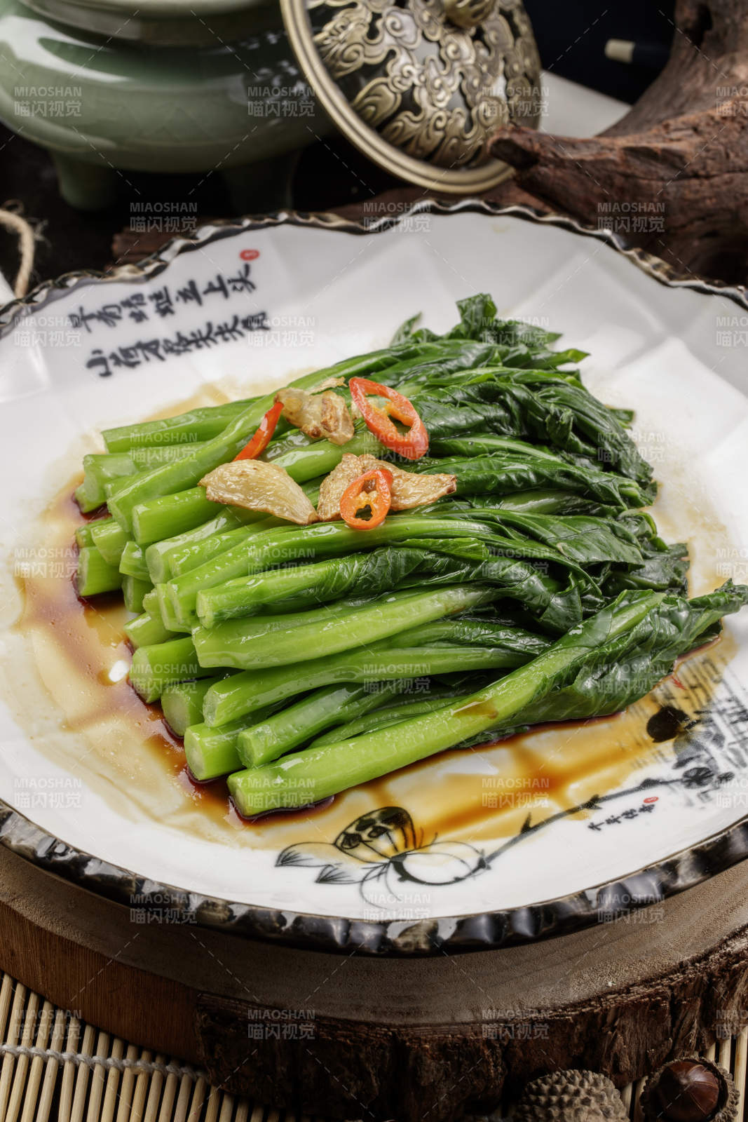 白色瓷盘装的炝炒芥蓝摆放在樟木砧板上图片